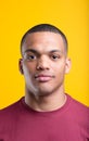 Subtly smiling Afro-American, muscular, yellow background