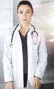 Intelligent professional woman-doctor is standing at the table in a sunny clinic office. Portrait of friendly female