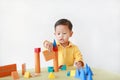 Intend asian little boy playing a wood block toy on table over white background