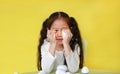 Intend asian little child girl playing plastic eggs developmental puzzle isolated on yellow background