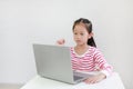 Intend asian little child sitting at desk and using laptop at home