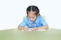 Intend little kid girl in school uniform writing on notebook at desk isolated over white background