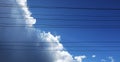 Intense blue sky contrasted against power line cables and ominous fluffy thunder clouds building up for a storm Royalty Free Stock Photo