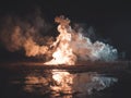Intense explosion with human silhouette made of smoke and fire, over a reflective water surface, captured from a ground-level Royalty Free Stock Photo