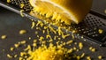 Macro Close-up of Vibrant Yellow Lemon Zest Being Grated with a Metal Microplane Grater onto a Dark Surface Royalty Free Stock Photo