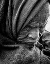 Intense monochrome close-up of elderly Indian woman\'s wrinkled face, eyes closed in profound reflection.