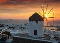 Intense sunset behind the famous windmill and the town of Mykonos island