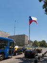 Intense traffic on Avenida La Alameda, the most important street in Santiago de Chile. In the background, the flag of Citizenship