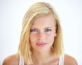 Intensity in her eyes. Head and shoulders portrait of a pretty young blonde standing in a studio.