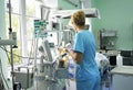 At the intensive care unit. Nurse standing near hospital bed with a baby preparing it for treatment