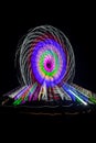 Intentional camera movement, slow shutter Zoom blur image of giant Ferris wheel illuminated and spinning at night in a funfair Royalty Free Stock Photo