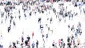 Intentionally blurred abstract aerial image of crowd of unrecognizable people walking in the city.