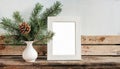 inter still life. Horizontal white frame mockup on vintage wooden bench, table. Modern white ceramic vase with pine tree branches Royalty Free Stock Photo