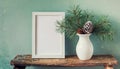 inter still life. Horizontal white frame mockup on vintage wooden bench, table. Modern white ceramic vase with pine tree branches Royalty Free Stock Photo