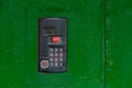 An intercom on green painted red steel surface with a keypad, digital display and rfid sensor for calling close-up