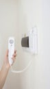 Intercom handset in a man`s hand against the background of a white wall in the room. The concept of modern intercoms with mute