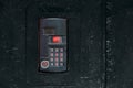 An intercom on old black painted steel surface with a keypad, digital display and rfid sensor for calling close-up