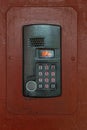 An intercom on old painted brown steel surface with a keypad, digital display and rfid sensor for calling close-up