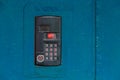 An intercom on old painted blue steel surface with a keypad, digital display and rfid sensor for calling close-up