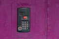An intercom on old painted pink steel surface with a keypad, digital display and rfid sensor for calling close-up