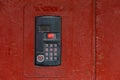 An intercom on old painted red steel surface with a keypad, digital display and rfid sensor for calling close-up