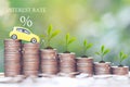 Interest rate and Banking concept, Miniature yellow car model and Plant growing on stack of coins money on natural green Royalty Free Stock Photo