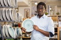 Interested african american man choosing plates in dishware store