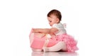 Interested baby girl try unpack gift box studio shot