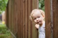 interested child looks out through a hole in a brown wooden fence. Royalty Free Stock Photo