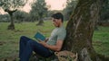 Interested gardener reading storybook evening nature closeup. Man leaning tree Royalty Free Stock Photo