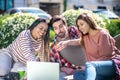 Interested guy and smiling girls on picnic in front of laptop Royalty Free Stock Photo