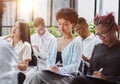 Interested happy young multiracial colleagues sitting on chairs, listening to male boss team leader Royalty Free Stock Photo