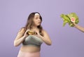 Interested hungry european young plus size lady in sportswear hold burger, look at hand with vegetables