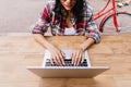 Interested latin girl working with laptop. Outdoor shot of good-humoured female student in checkere