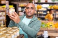 Interested man reading jar contents on label in supermarket