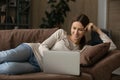 Young female lying on sofa working from home on laptop Royalty Free Stock Photo