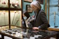 Preteen girl and elderly woman in protective masks viewing antique handguns in museum