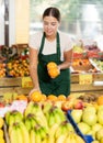 Interested salesgirl laying out oranges on display stand in supermarket Royalty Free Stock Photo