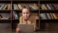 Interested schoolgirl plays online game on tablet in library