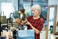 Interested senior lady choosing fall footwear in shoe store Royalty Free Stock Photo