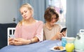 Teenage boy and his mother sitting at home table with smartphones Royalty Free Stock Photo