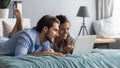 Interested young couple lying on bed, looking at computer screen. Royalty Free Stock Photo