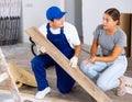Young woman talking to builder during laminate flooring installation in apartment