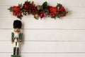 Interesting beautiful Christmas ornaments decorations with nutcracker soldier on white colored wooden surface texture with copy sp Royalty Free Stock Photo