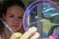 Interesting beautiful young woman looks at herself in the mirror and sticks with the cutter knife glittering stones in the face Royalty Free Stock Photo