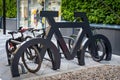 Interesting bike rack stand in shape of large bicycle with numerous bikes parked at it in urban shopping location. Royalty Free Stock Photo