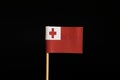 A interesting flag of Tonga on wooden stick on black background. Tonga belongs to oceania