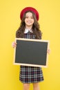 Interesting school lesson. Little child holding blank blackboard for private lesson on yellow background. Cute pupil