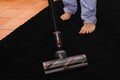 Interesting shot of a male cleaning the black carpet with a vacuum cleaner