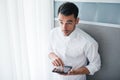 Interesting view from above of handsome businessman working with a device, gadget in his hands, standing in front of a window and Royalty Free Stock Photo